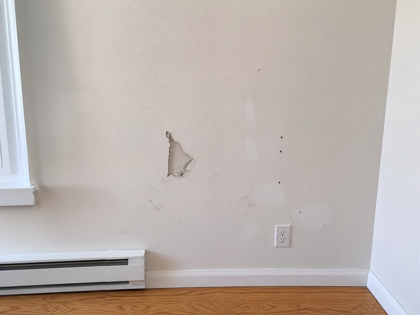 Damaged drywall before patching and paint touch-up